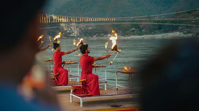 Ganga Aarti at Shatrughan Ghat, Rishikesh — priests raising brass fire lamps over the Ganges