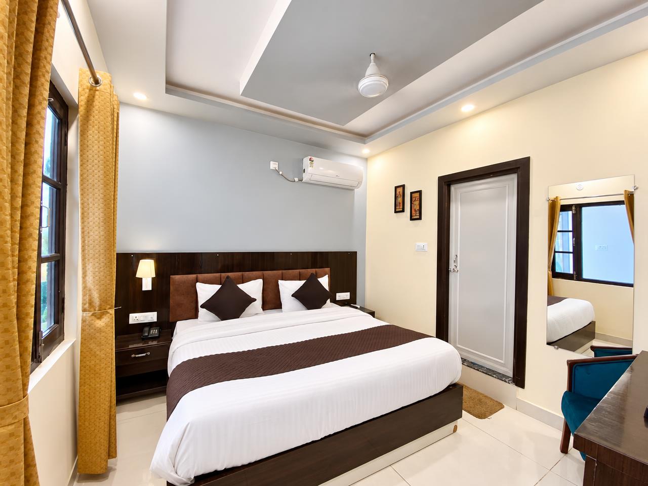 Comfort room at Tapovan New Residency, Rishikesh — queen bed, warm lighting and golden curtains